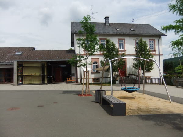 Die Kita Munzelsmännchen im ehemaligen Schulhaus, davor der Spielplatz mit Nestschaukel